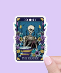 Sticker of 'The Reader' tarot card held by a hand against a purple background