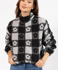 Woman wearing a black and gray checkered jacket with floral patterns on a white background