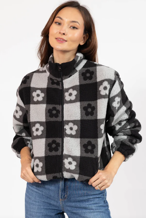 Woman wearing a black and gray checkered jacket with floral patterns on a white background