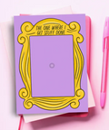 Notepad with yellow frame design and text on purple background, pink pen on side