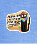 Sticker with a cartoon character wearing a cowboy hat and rainbow bandana, text 'Actually this is my first rodeo (and I'm scared as fuck)' on a blue textured background.