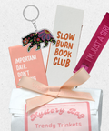 Collection of trendy trinkets including a keychain, book club card, and wristband on a white background.