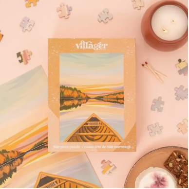 Villager puzzle box with a scenic design on a pink background with puzzle pieces and a candle.