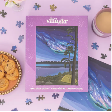 Villager puzzle box with a scenic design on a table with cookies and tea.