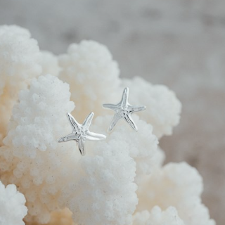 Silver starfish earrings on a textured white surface