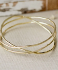 Gold bangles on a textured beige surface