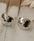 Pair of silver earrings on a textured surface with a wooden background