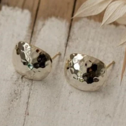 Pair of silver earrings on a textured surface with a wooden background