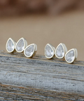 Teardrop-shaped earrings on a wooden surface with a blurred background