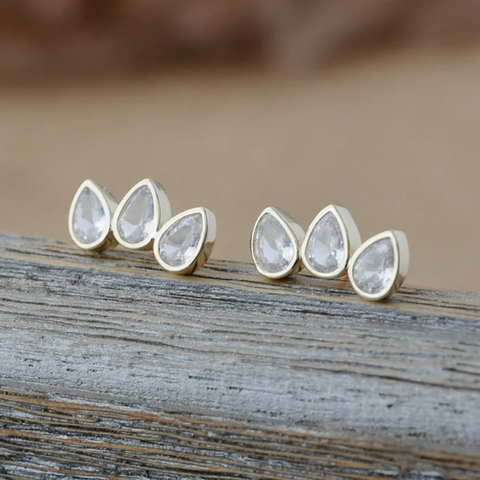 Teardrop-shaped earrings on a wooden surface with a blurred background