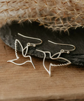 Silver butterfly earrings on a wooden surface with a natural background