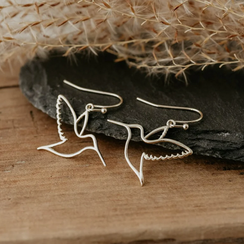 Silver butterfly earrings on a wooden surface with a natural background