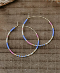 Pair of beaded hoop earrings on a wooden surface