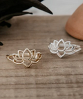Gold and silver lotus flower rings on a wooden surface