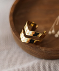 Gold ring on a wooden dish with a white fabric background