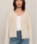 A woman modeling a cream-colored, long-sleeve knit cardigan over a white top and blue jeans, set against a plain light gray studio background.