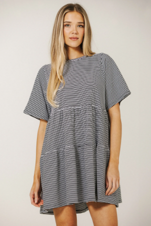 Woman wearing a black and white striped dress against a plain background