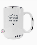 White mug with black text 'you're my favorite husband' and a heart on a white background