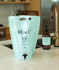 A blue refill pouch labeled 'Mint' for dish soap placed on a kitchen countertop with a bottle in the background.